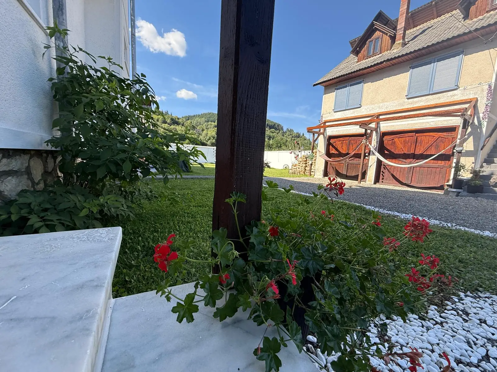 Curtea cabanei cu flori și vedere spre dealuri