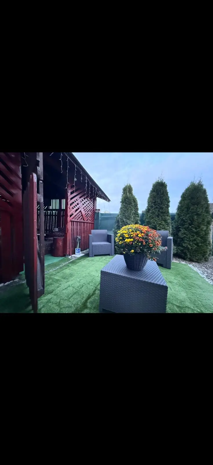 Zonă de relaxare cu fotolii și flori în curte